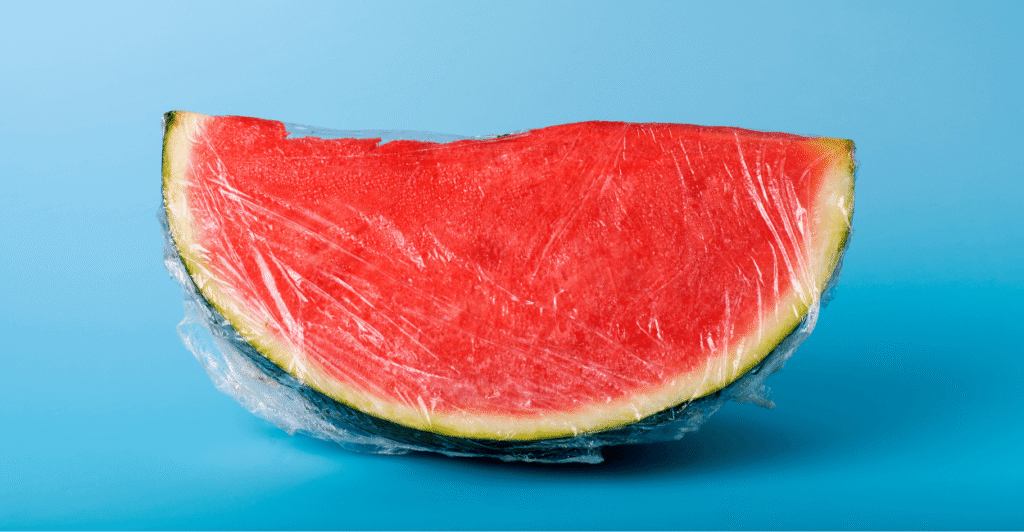 cut watermelon cubes covered with plastic wrap on a kitchen counter