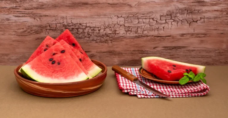 Glass bowl filled with fresh watermelon cubes, partially covered with plastic wrap, placed on a light kitchen counter